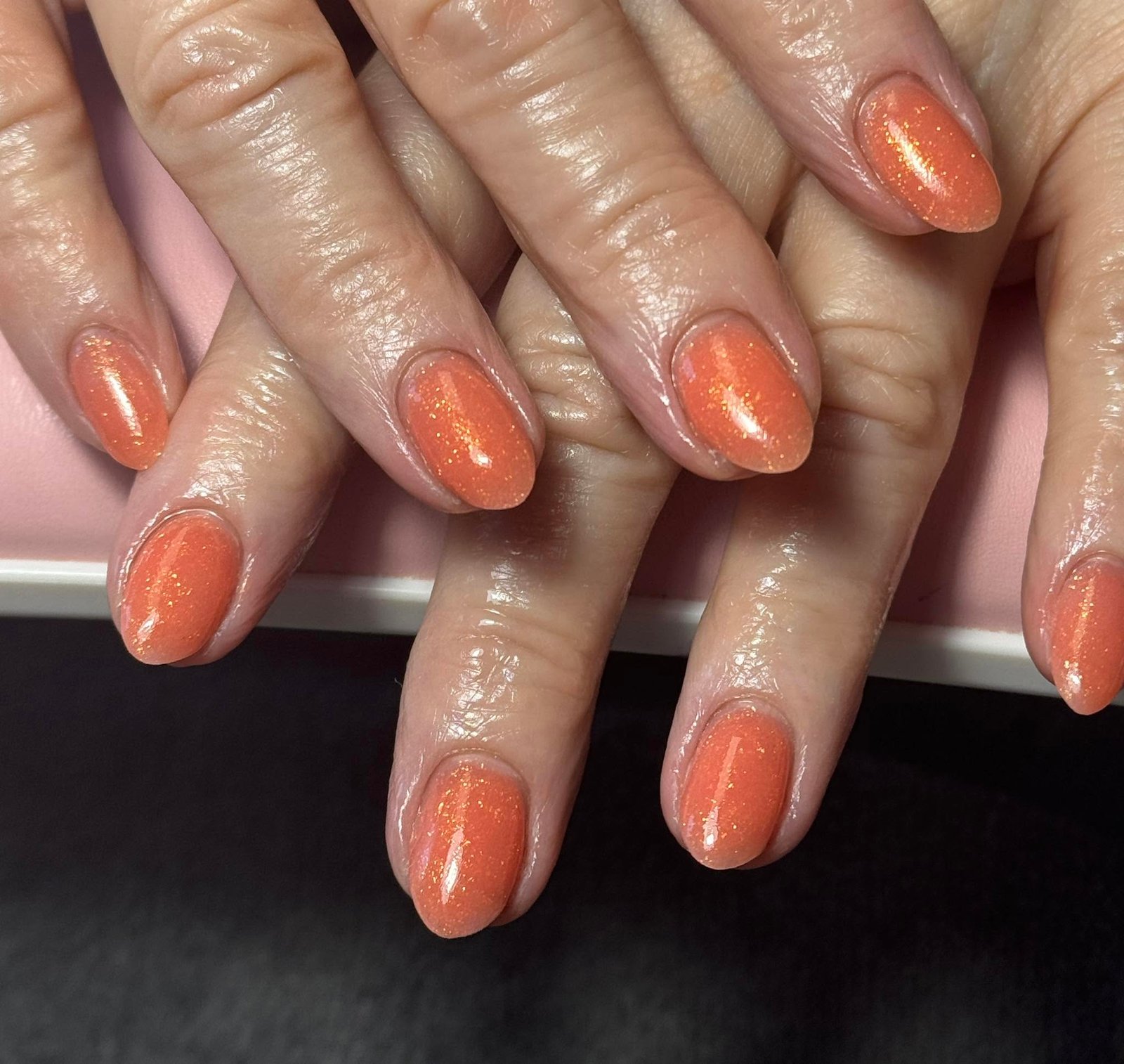 Coral orange gel manicure with fine gold shimmer