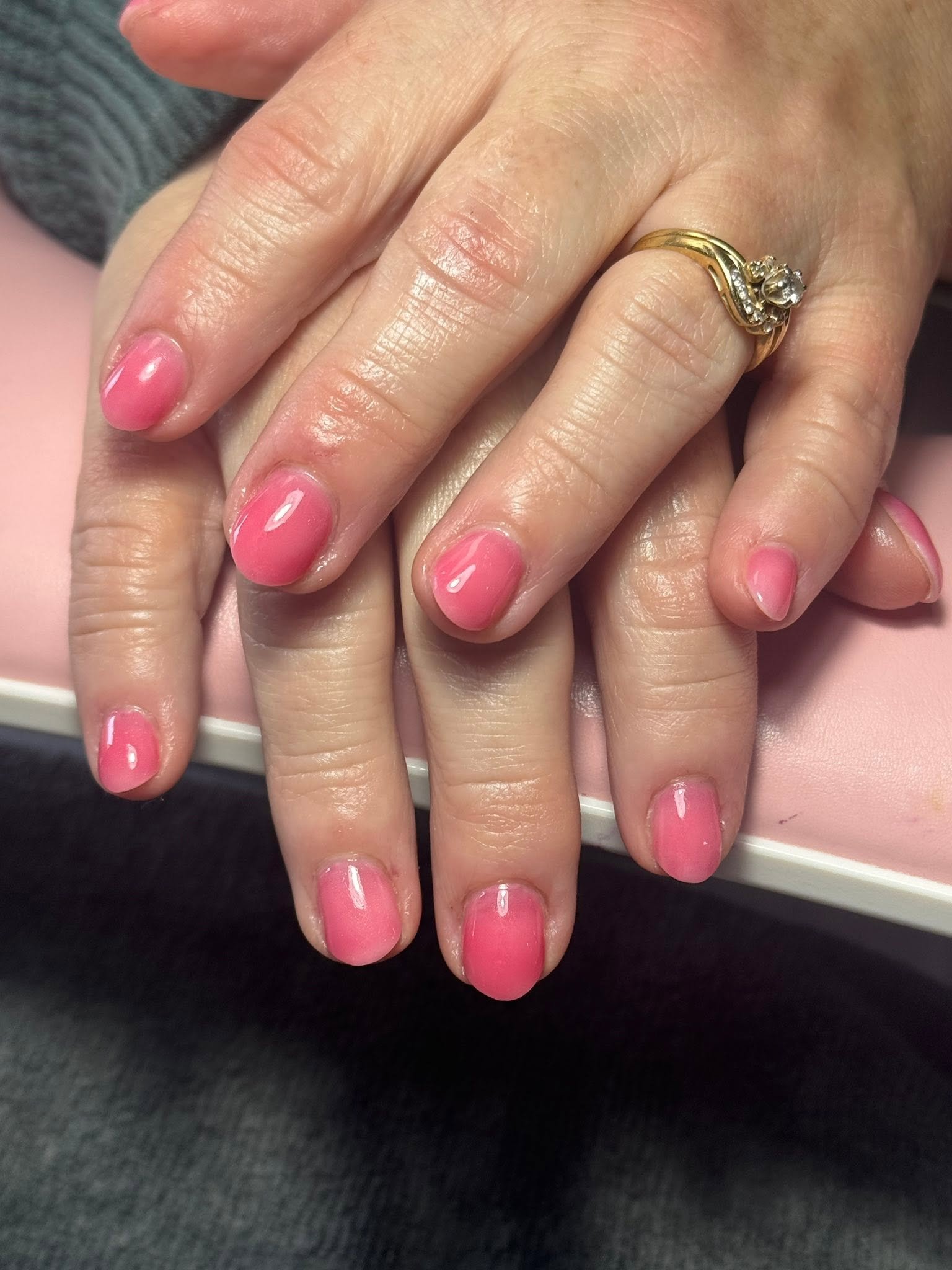 Glossy coral pink solid gel manicure with a gold ring
