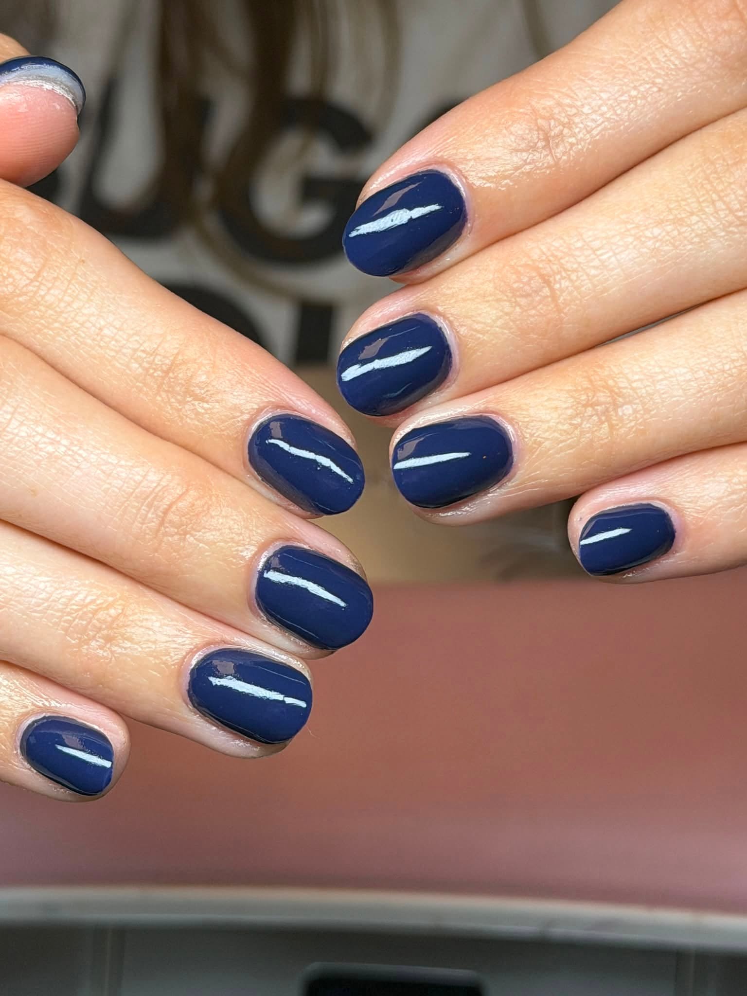 Navy blue glossy nails with a white brushstroke accent