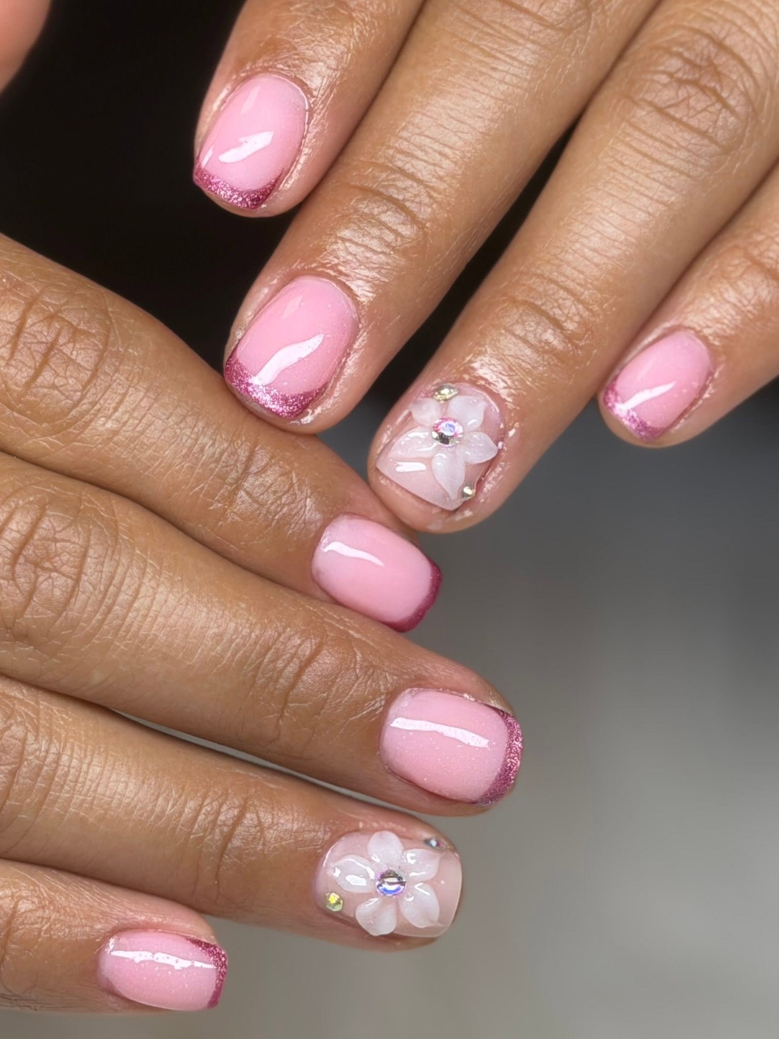 Pink French nails with a 3D flower and rhinestone accent