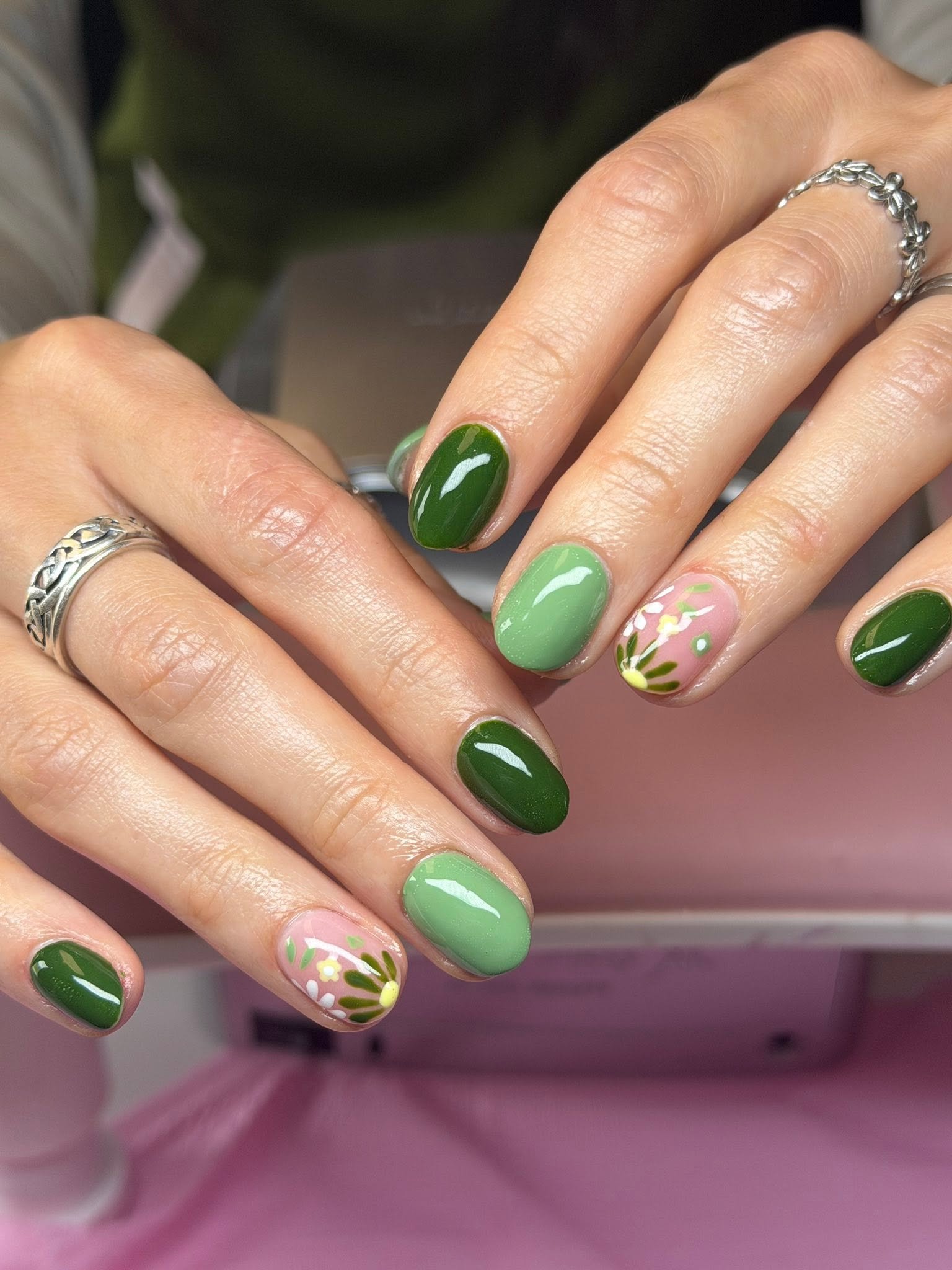 Green nails with a hand-painted floral accent