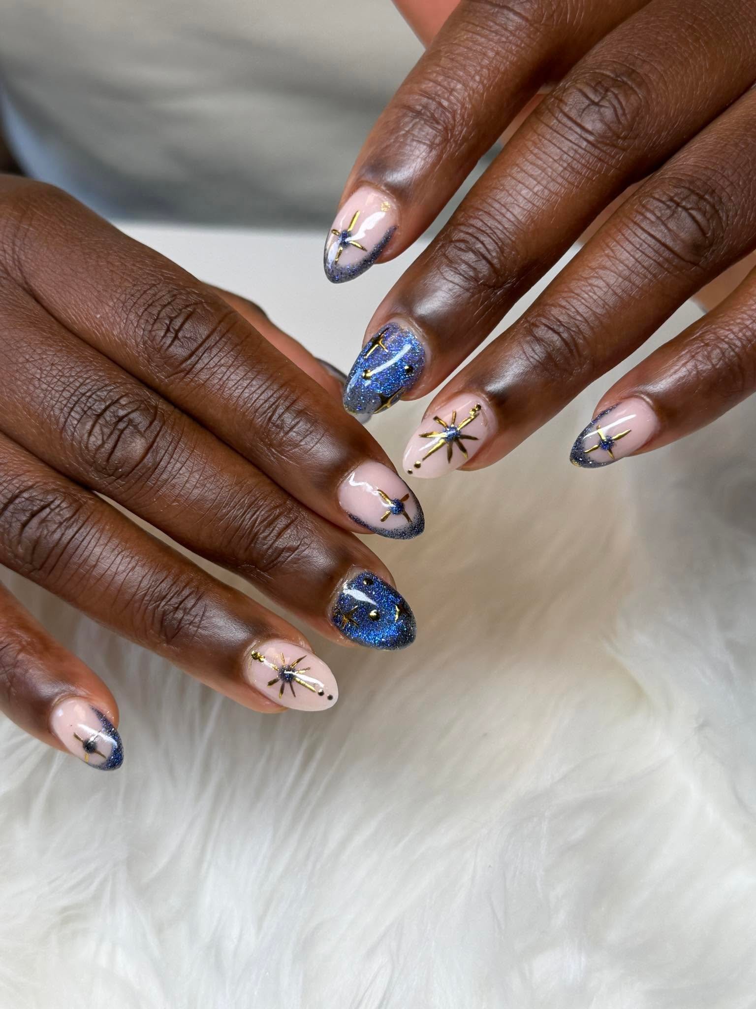 Navy glitter nails with a gold starburst design