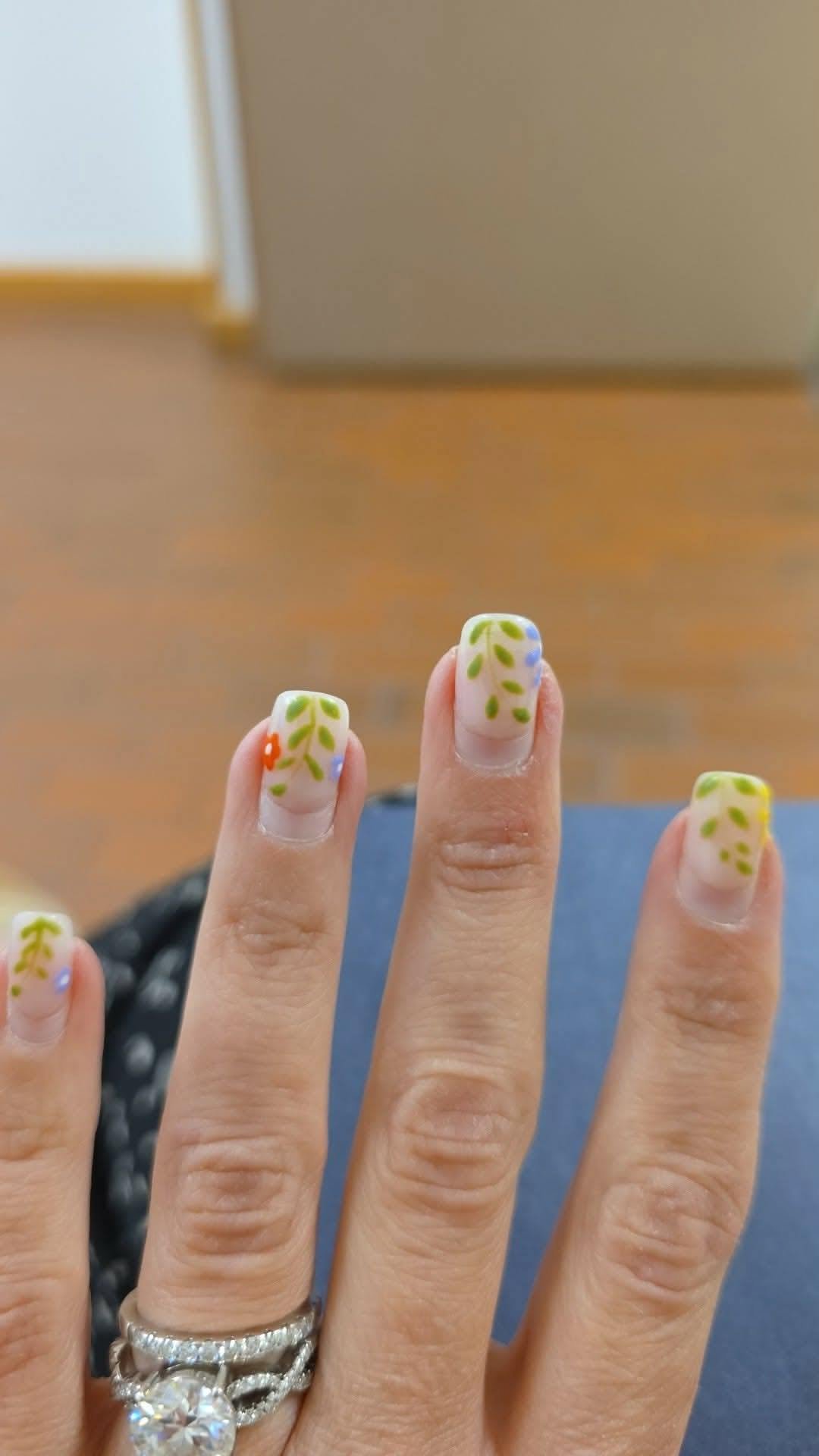 Nude nails with hand-painted green vine and floral accents