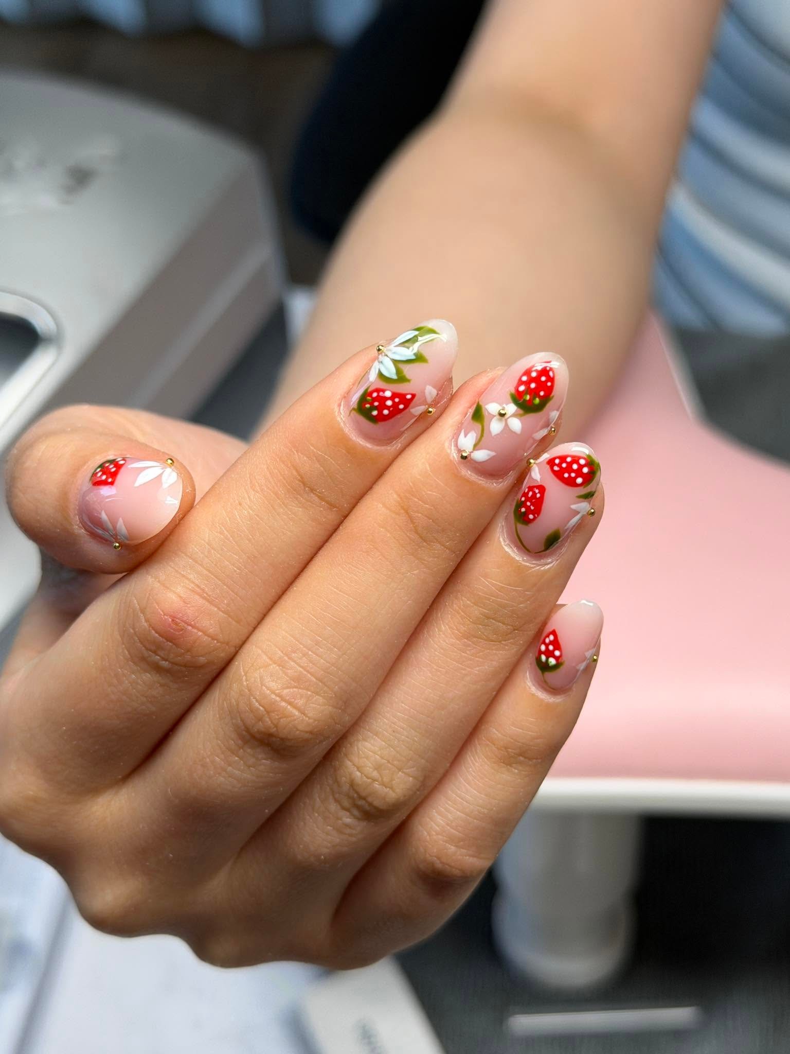 Sheer nails with painted strawberries, flowers, and gold studs