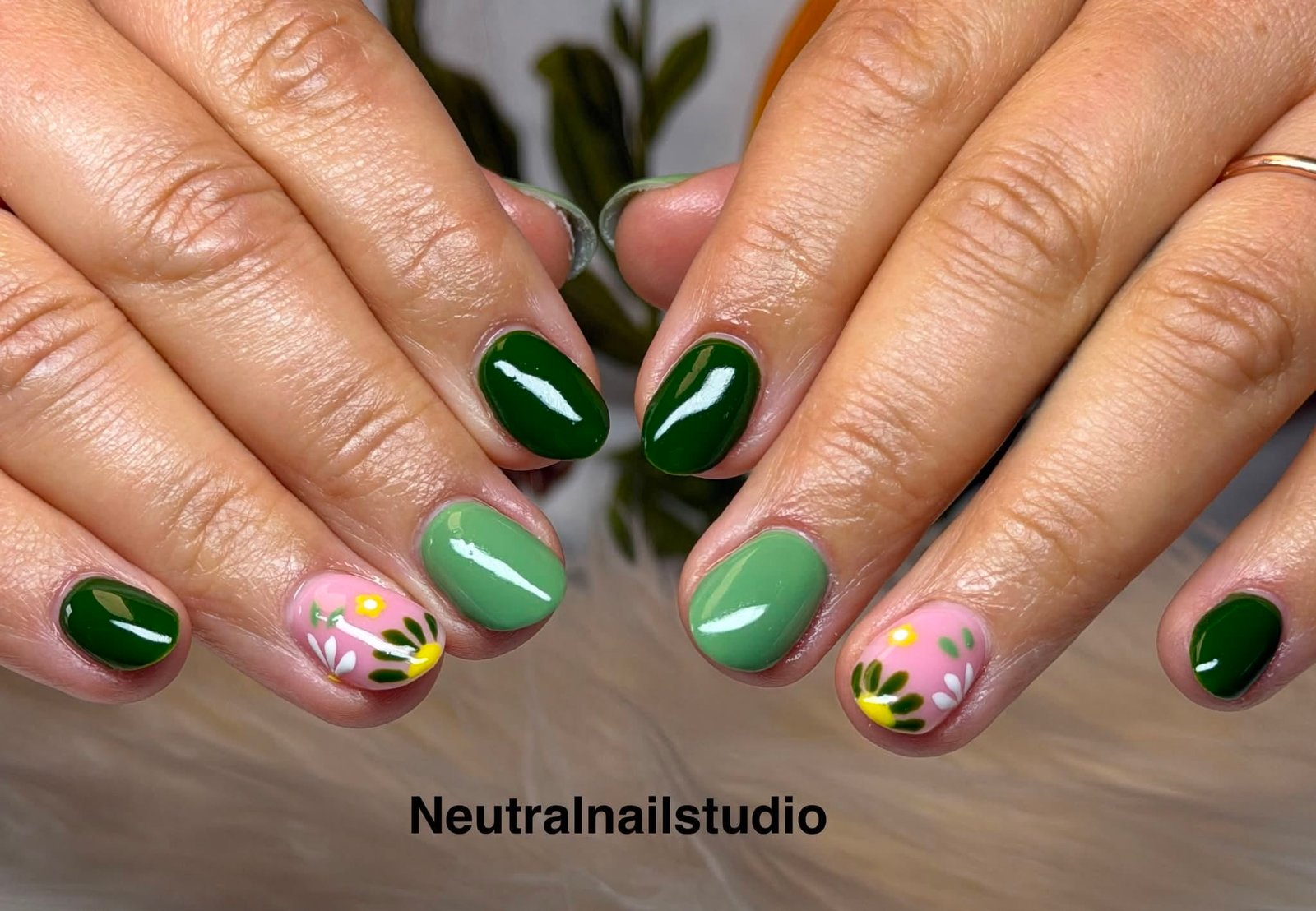 Green gel manicure with a hand-painted yellow flower accent