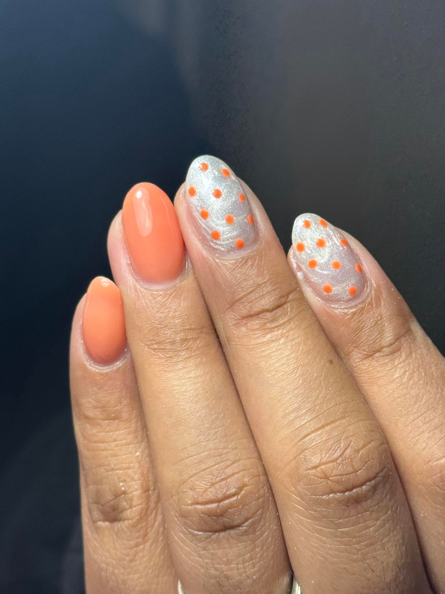 Orange nails with silver glitter and orange polka dot accents