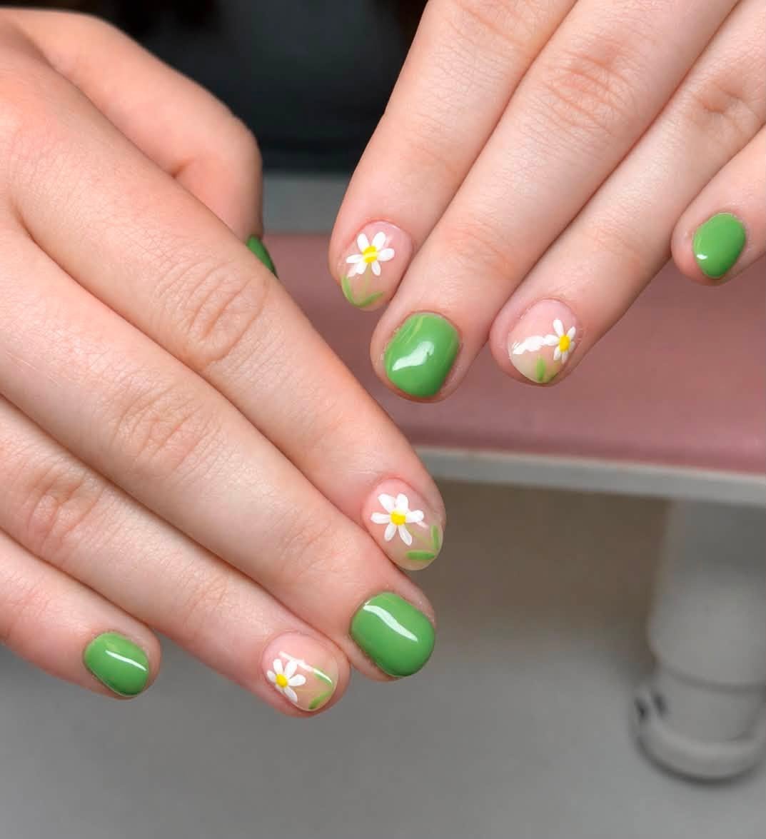 Green manicure with daisy flowers on both hands